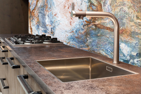 Modern designer chrome water tap over stainless steel kitchen sink.